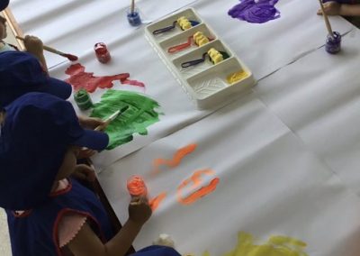 An image of kids painting on a big canvas in the early childcare center.