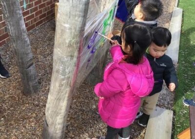 An image of kids painting on plastic material in the st albans childcare.